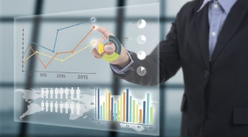 Consultant pointing at colorful bar charts and graphs on a glass display, illustrating data-driven pricing analysis